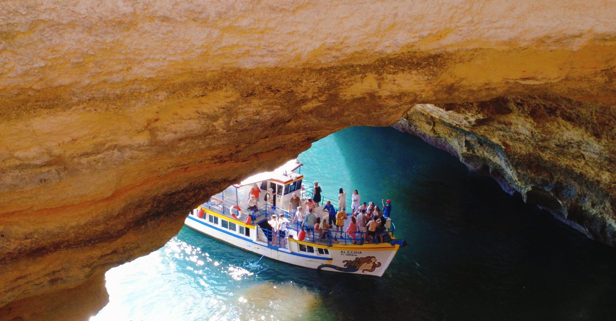 a boat entering an ocean cave. Cliff walls and sea water.